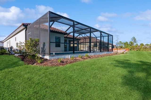 rear view of property featuring a yard and glass enclosure