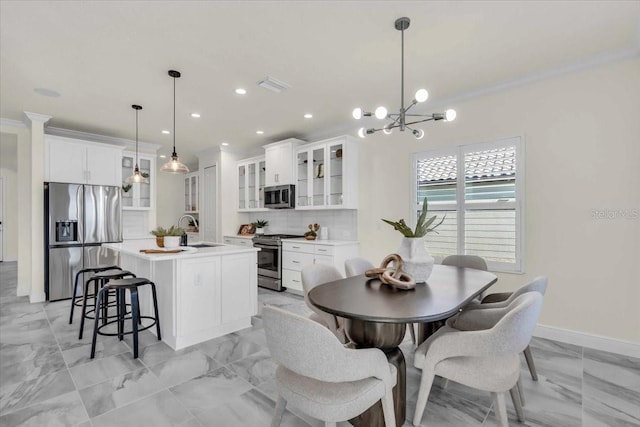 dining room with crown molding, sink, and an inviting chandelier