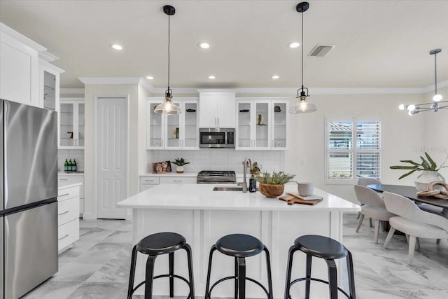 kitchen featuring white cabinets, pendant lighting, an island with sink, and stainless steel appliances