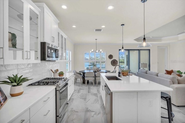 kitchen with decorative backsplash, white cabinetry, sink, and appliances with stainless steel finishes