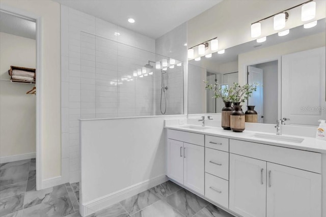 bathroom with a tile shower and vanity