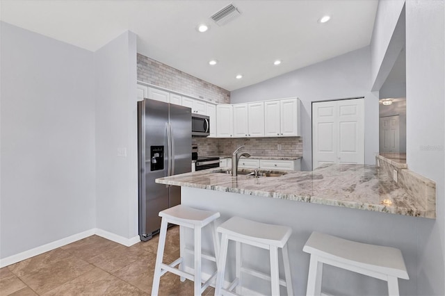 kitchen with white cabinetry, kitchen peninsula, appliances with stainless steel finishes, vaulted ceiling, and sink