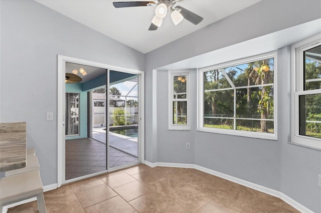 interior space with lofted ceiling, ceiling fan, a wealth of natural light, and light tile patterned flooring