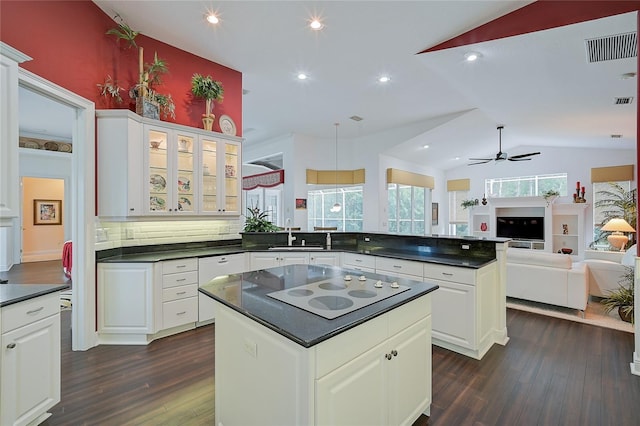 kitchen with white cabinetry, dark wood-type flooring, tasteful backsplash, vaulted ceiling, and a kitchen island