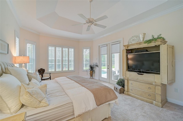 bedroom featuring access to exterior, a tray ceiling, multiple windows, and light colored carpet