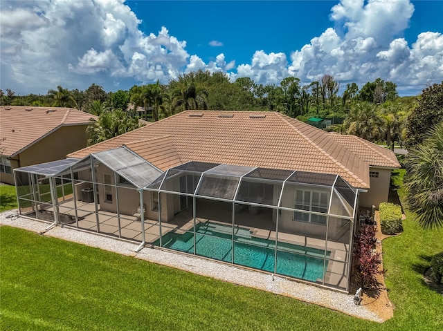 rear view of property featuring a lawn, glass enclosure, and a patio