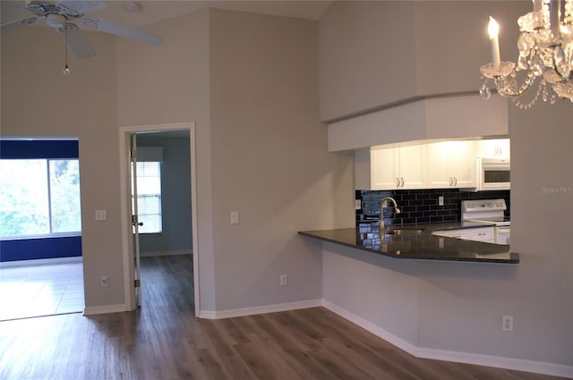 kitchen featuring ceiling fan with notable chandelier, white appliances, white cabinets, a towering ceiling, and sink