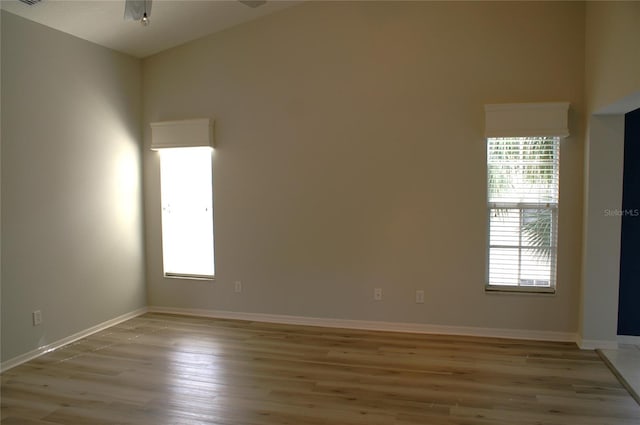 spare room with light wood-type flooring, ceiling fan, and plenty of natural light