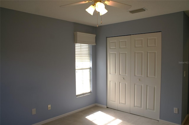 unfurnished bedroom featuring light carpet, ceiling fan, and a closet