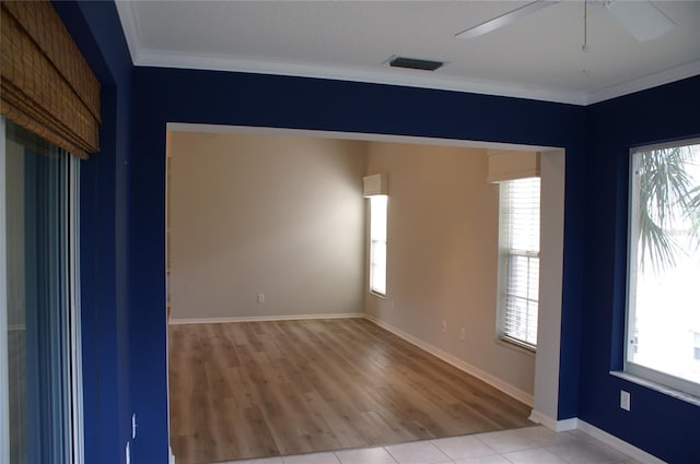 tiled empty room with crown molding and a healthy amount of sunlight