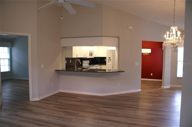 unfurnished living room featuring high vaulted ceiling, dark wood-type flooring, and ceiling fan with notable chandelier