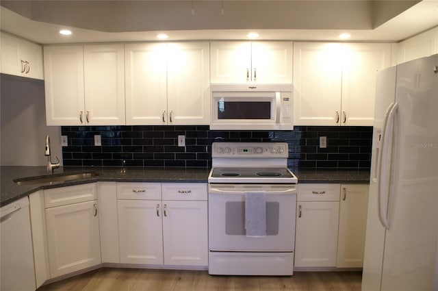 kitchen featuring dark stone countertops, decorative backsplash, sink, white appliances, and white cabinets