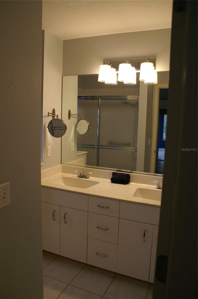 bathroom with a shower with shower door, vanity, tile patterned flooring, and a textured ceiling