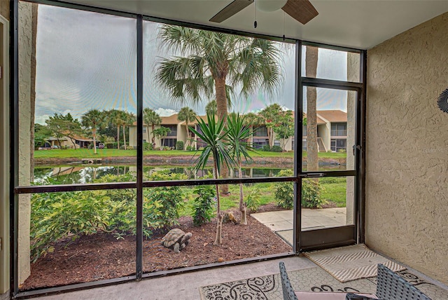 unfurnished sunroom with ceiling fan and a water view