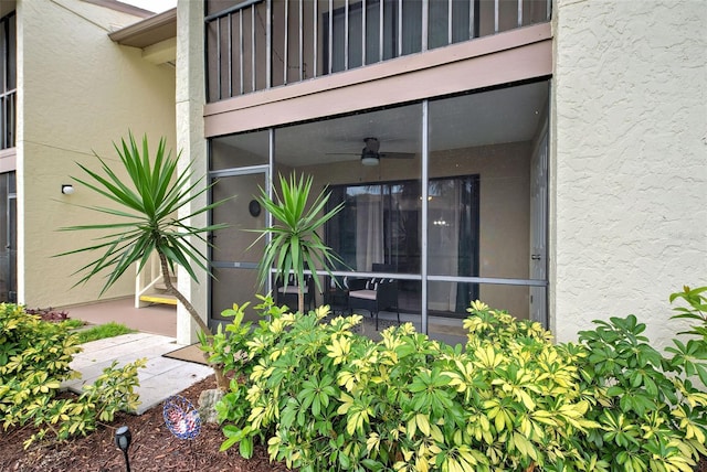 doorway to property with ceiling fan and a balcony