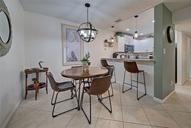 tiled dining space with a textured ceiling and an inviting chandelier