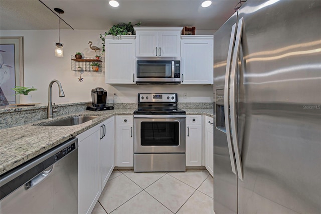 kitchen with hanging light fixtures, sink, light tile patterned floors, appliances with stainless steel finishes, and white cabinetry