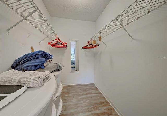 walk in closet with light hardwood / wood-style floors