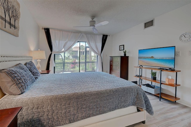 bedroom featuring ceiling fan, light hardwood / wood-style floors, and a textured ceiling