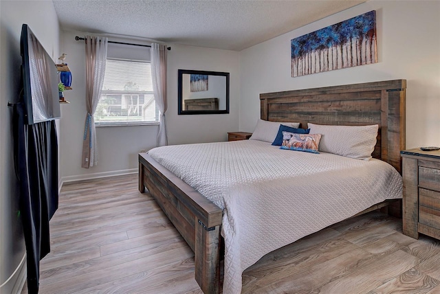 bedroom featuring a textured ceiling and light hardwood / wood-style floors