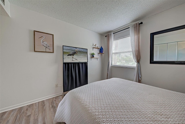 bedroom with light hardwood / wood-style floors and a textured ceiling