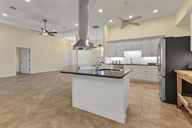 kitchen featuring visible vents, a sink, tasteful backsplash, dark countertops, and freestanding refrigerator