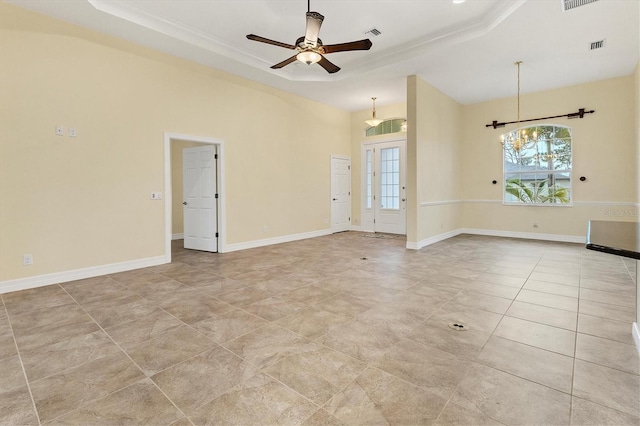 tiled empty room with ceiling fan, a tray ceiling, baseboards, and ornamental molding