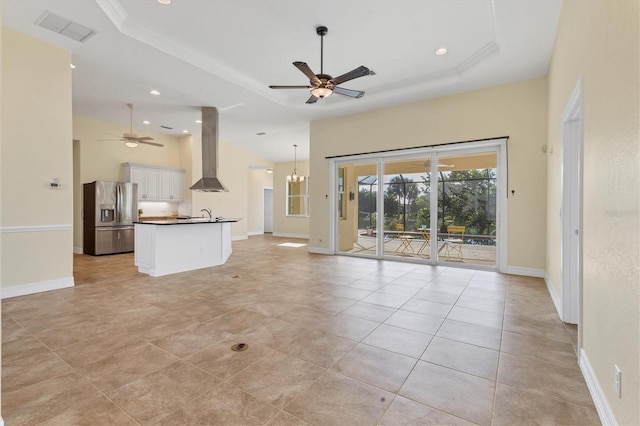 unfurnished living room featuring a tray ceiling, baseboards, visible vents, and ceiling fan with notable chandelier