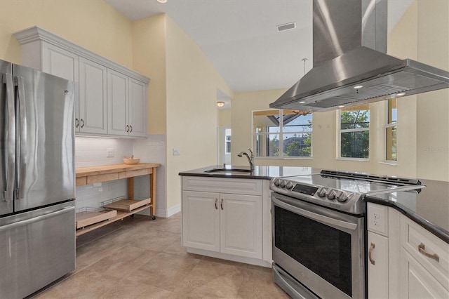 kitchen with visible vents, a sink, dark countertops, appliances with stainless steel finishes, and wall chimney range hood