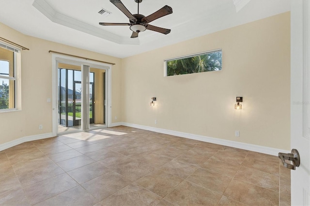 spare room with a wealth of natural light, a tray ceiling, baseboards, and visible vents