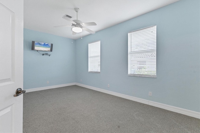 unfurnished room with visible vents, carpet floors, baseboards, and ceiling fan