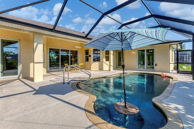 outdoor pool featuring glass enclosure, a patio, and a ceiling fan