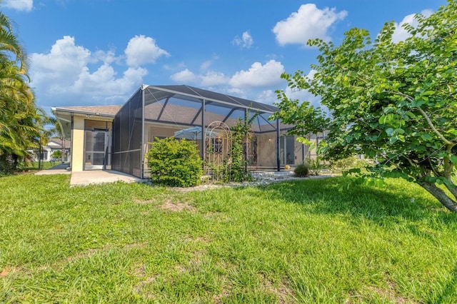 back of house with glass enclosure, a patio area, a lawn, and stucco siding