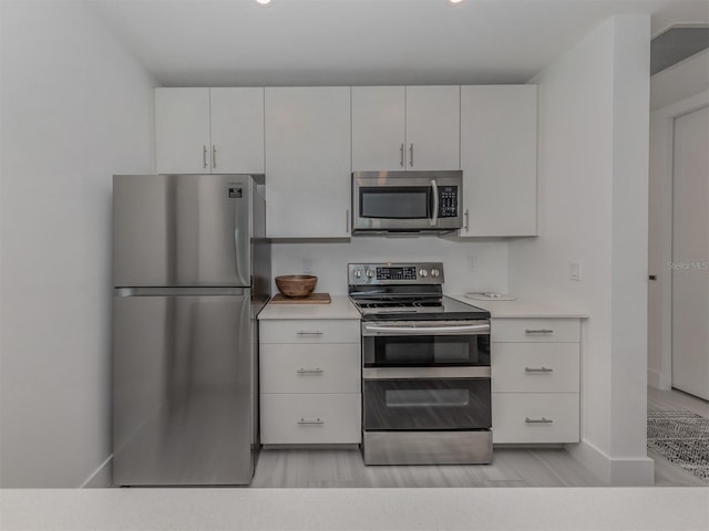 kitchen featuring appliances with stainless steel finishes, light hardwood / wood-style floors, and white cabinetry