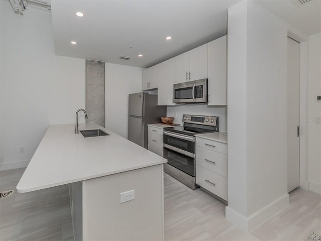 kitchen featuring appliances with stainless steel finishes, a center island, white cabinetry, and sink