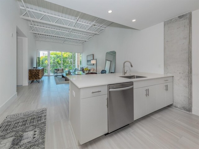 kitchen featuring stainless steel dishwasher, kitchen peninsula, white cabinetry, and sink