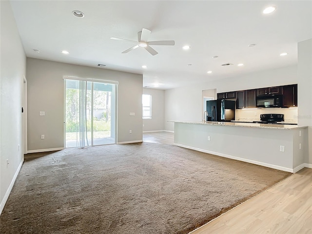 kitchen featuring black appliances, light colored carpet, ceiling fan, and light stone counters