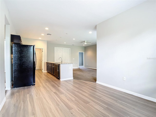 kitchen featuring light stone countertops, sink, light hardwood / wood-style flooring, and an island with sink