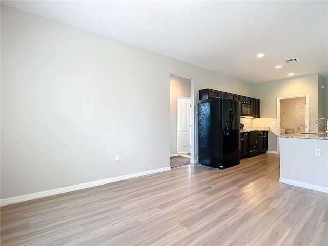 kitchen featuring black appliances, light stone countertops, sink, and light hardwood / wood-style floors