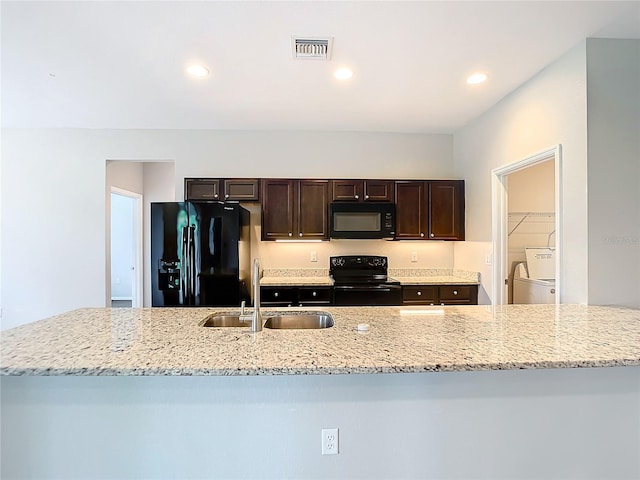 kitchen with light stone countertops, sink, black appliances, and dark brown cabinets