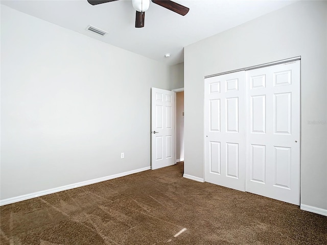 unfurnished bedroom featuring ceiling fan, dark carpet, and a closet