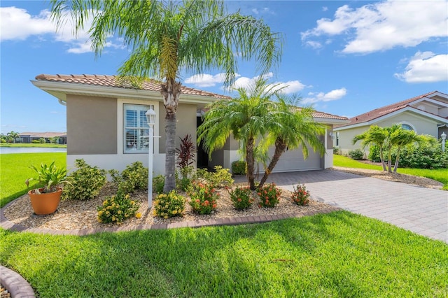 mediterranean / spanish-style house featuring a tile roof, a front yard, stucco siding, decorative driveway, and an attached garage