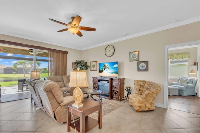 living area with light tile patterned floors, baseboards, a ceiling fan, and ornamental molding