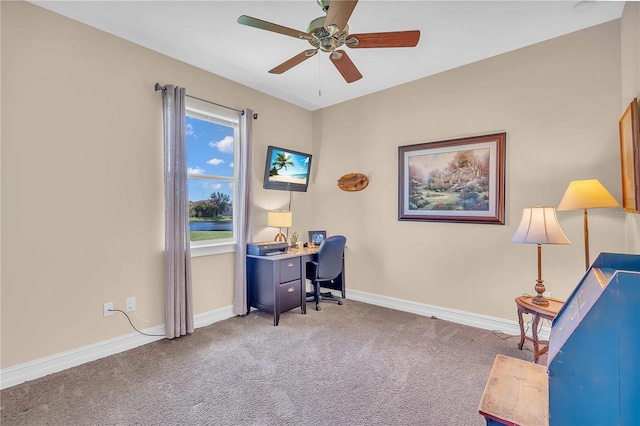 carpeted office space featuring ceiling fan and baseboards