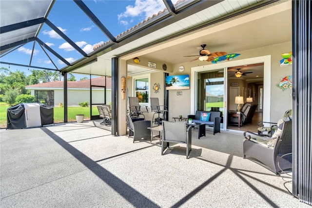 view of patio with ceiling fan, area for grilling, and glass enclosure