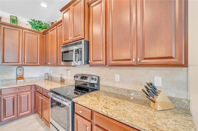 kitchen featuring light stone counters, stainless steel appliances, light tile patterned flooring, and decorative backsplash