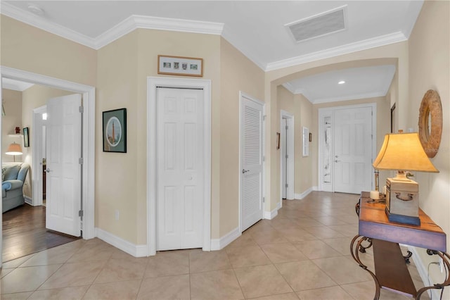 hall featuring visible vents, baseboards, light tile patterned flooring, and crown molding