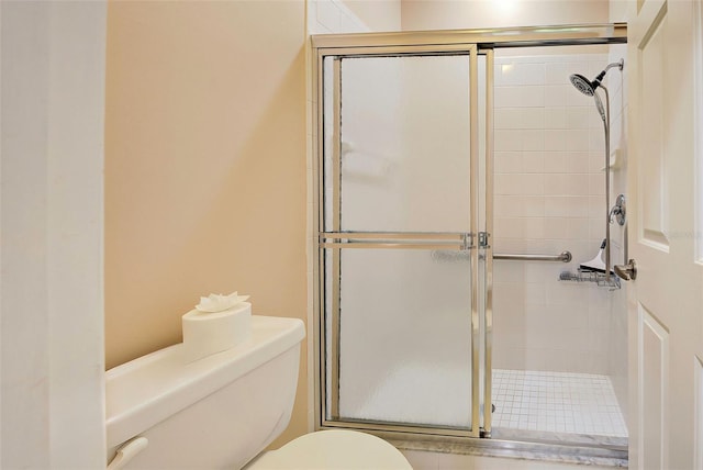 bathroom featuring a shower with door and toilet