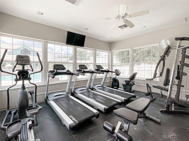 gym with ceiling fan and a textured ceiling