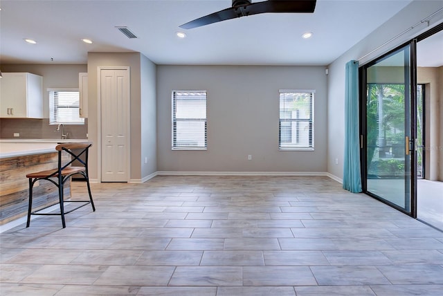 interior space with ceiling fan, white cabinetry, a wealth of natural light, and tasteful backsplash